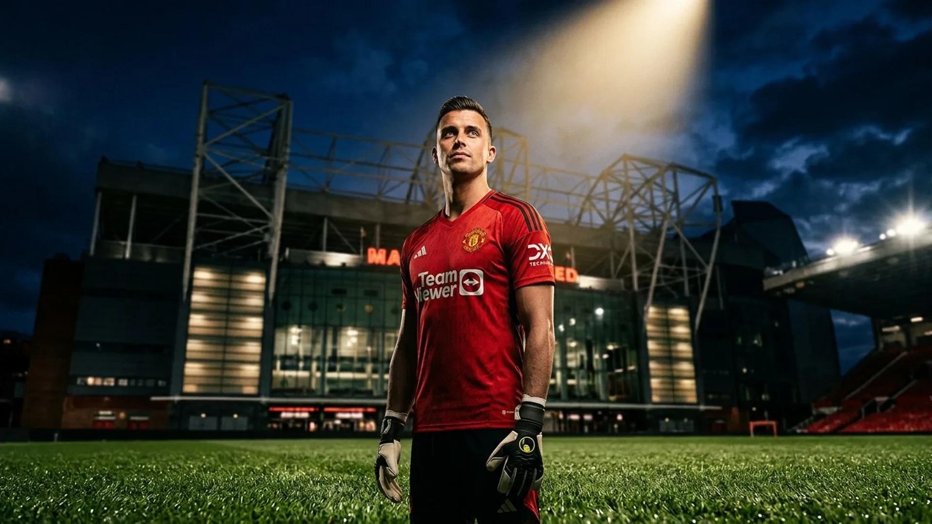 A male goalkeeper stands in front of Old Trafford, illuminated by a spotlight.