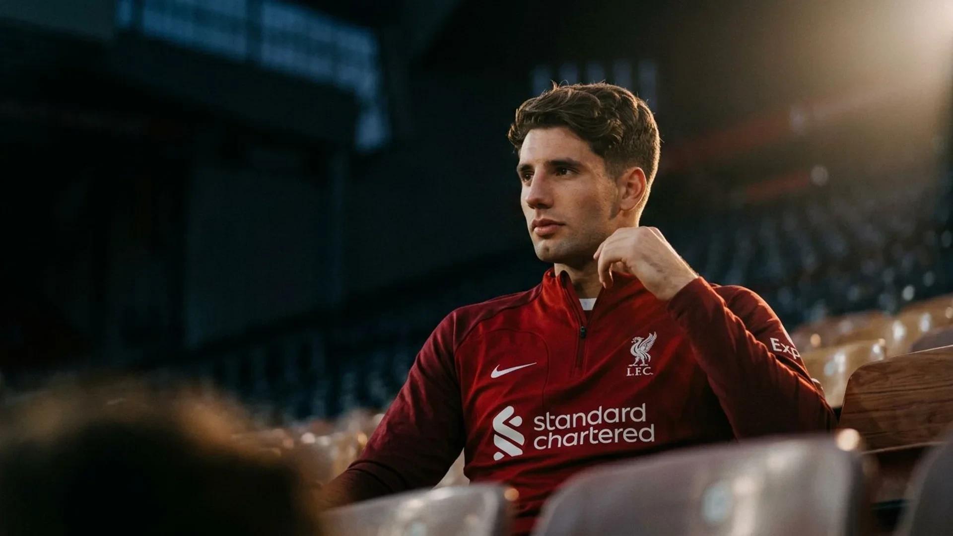 Dominik Szoboszlai sits in a dimly lit Anfield stadium with a determined expression.