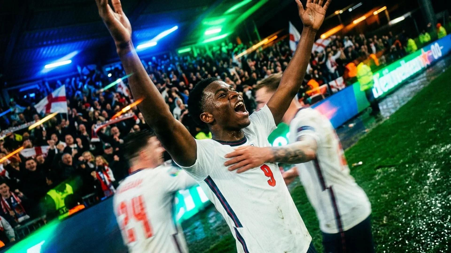 Bukayo Saka celebrating a goal in a crowded stadium, captured from a tilted angle.
