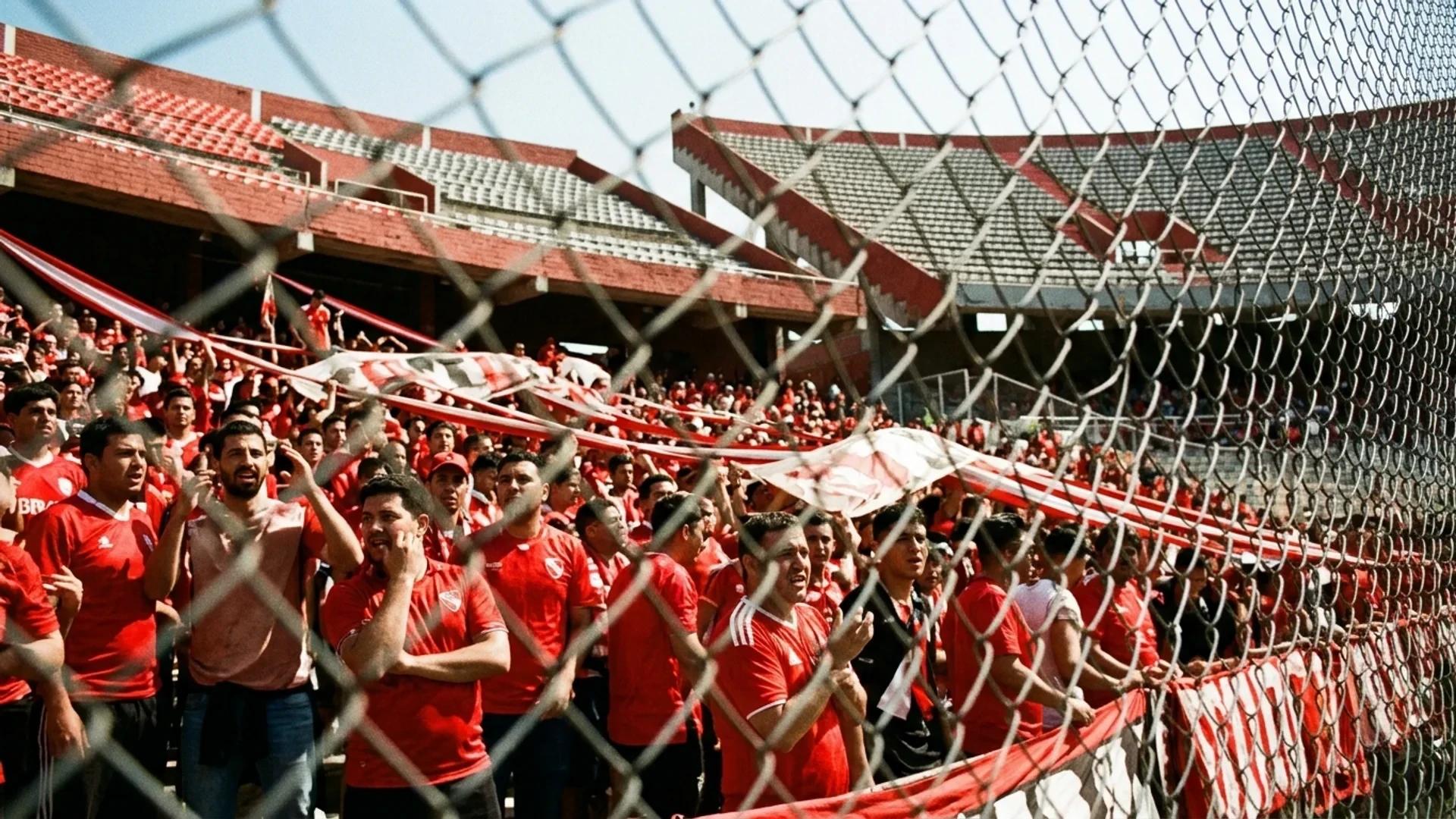 A Dutch angle view of Anfield stadium with fans expressing concern, highlighted by harsh midday sunlight.
