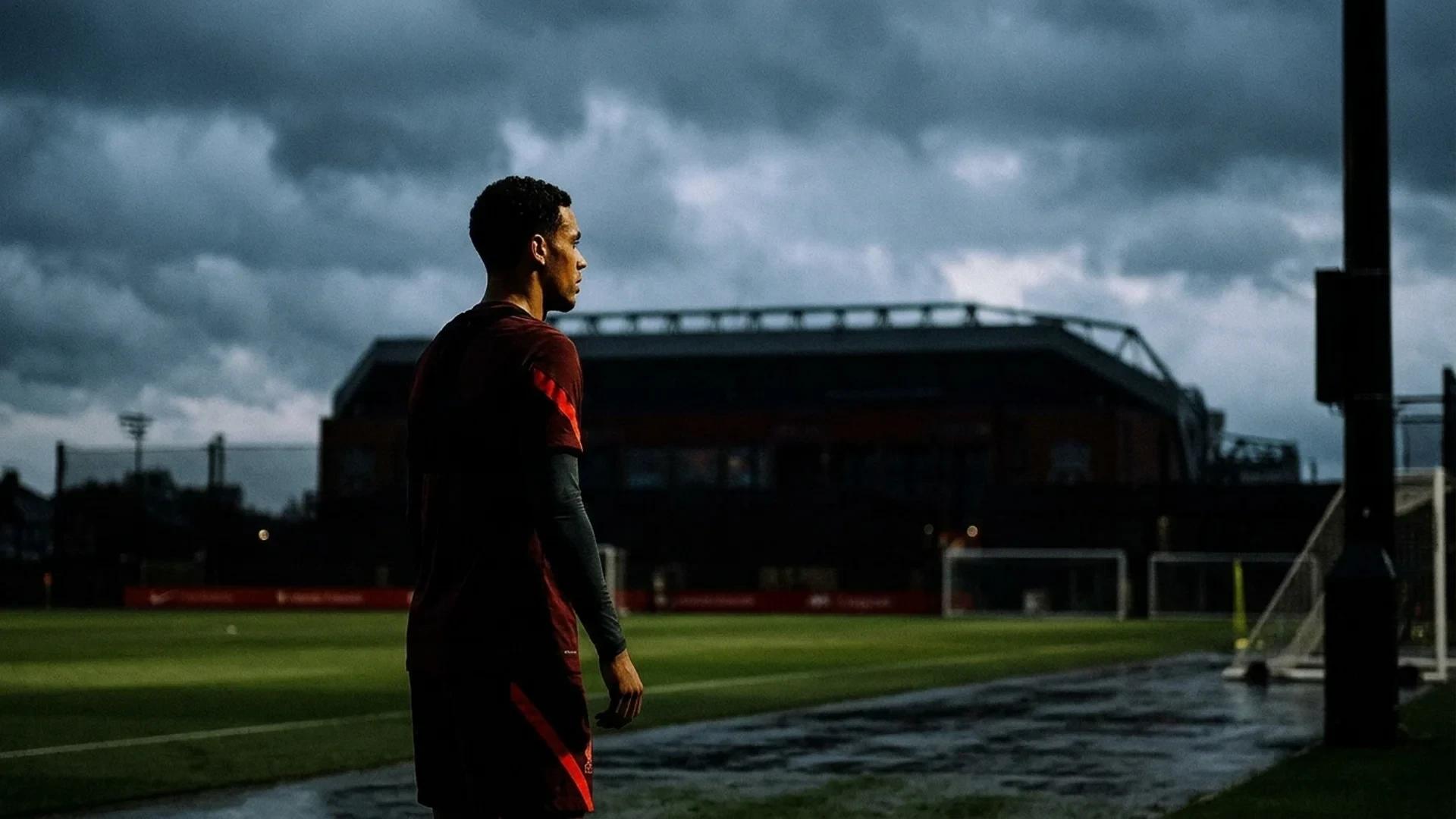 A Liverpool FC player stands alone in a training ground, illuminated by dramatic lighting with Anfield in the background.