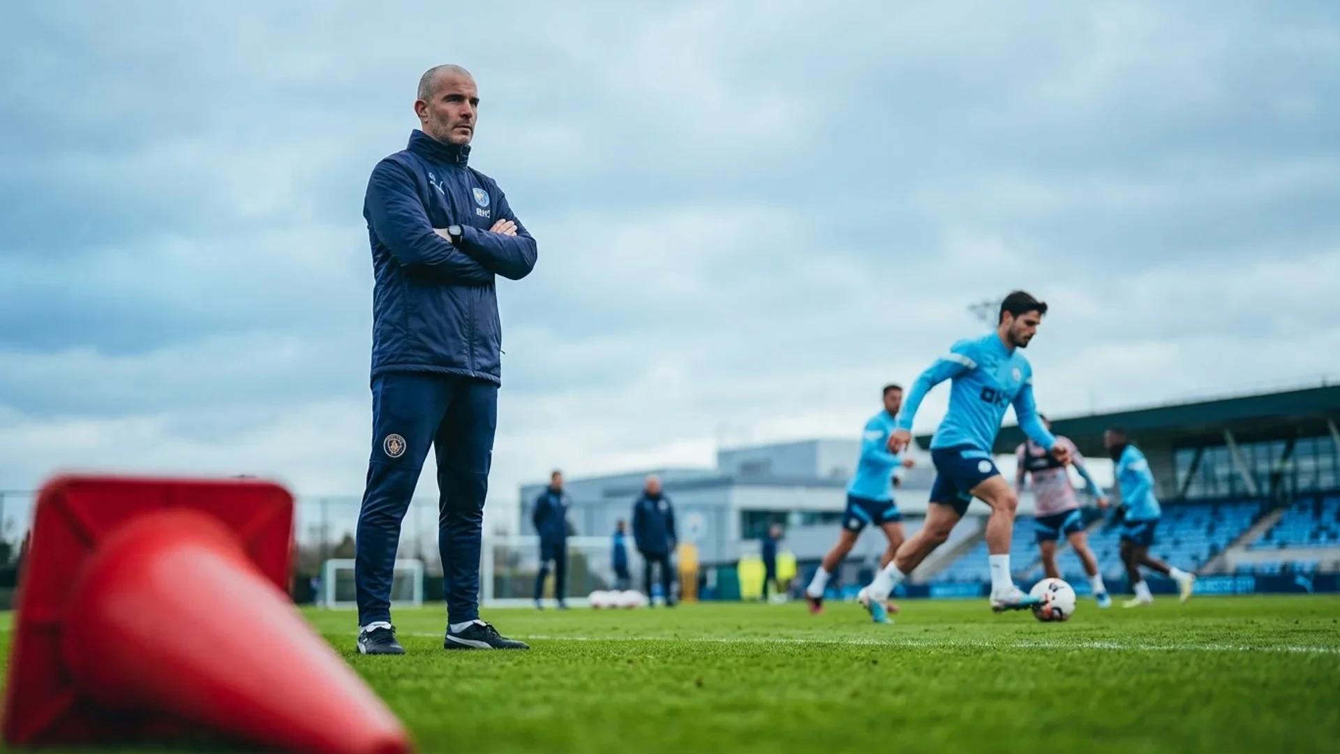Enzo Maresca observing a training session with blurred players in the background.