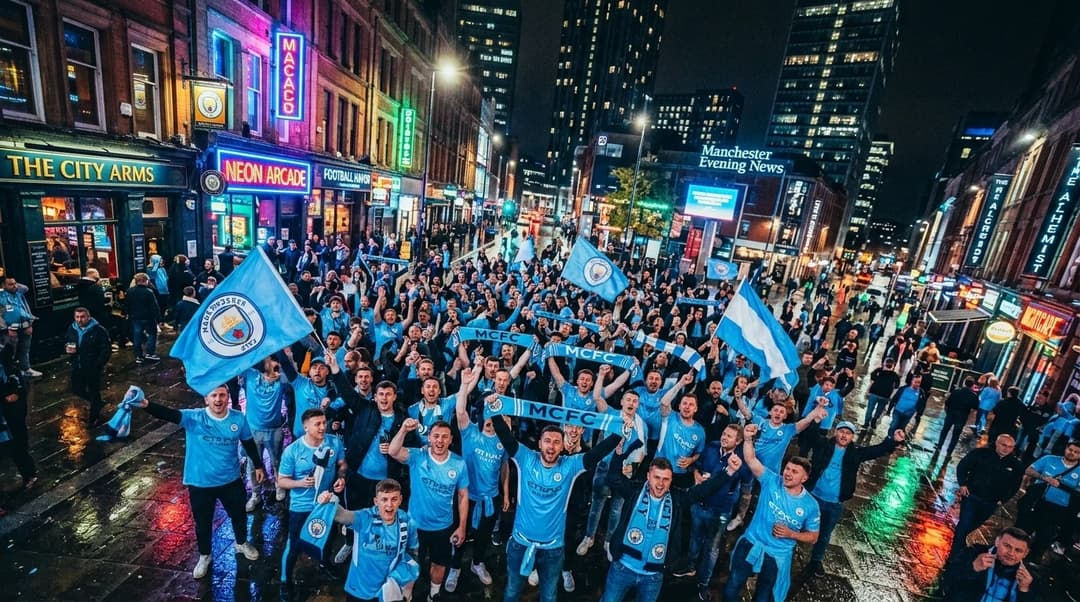 Folk samles under neonlys i en bygate for å støtte Manchester City.