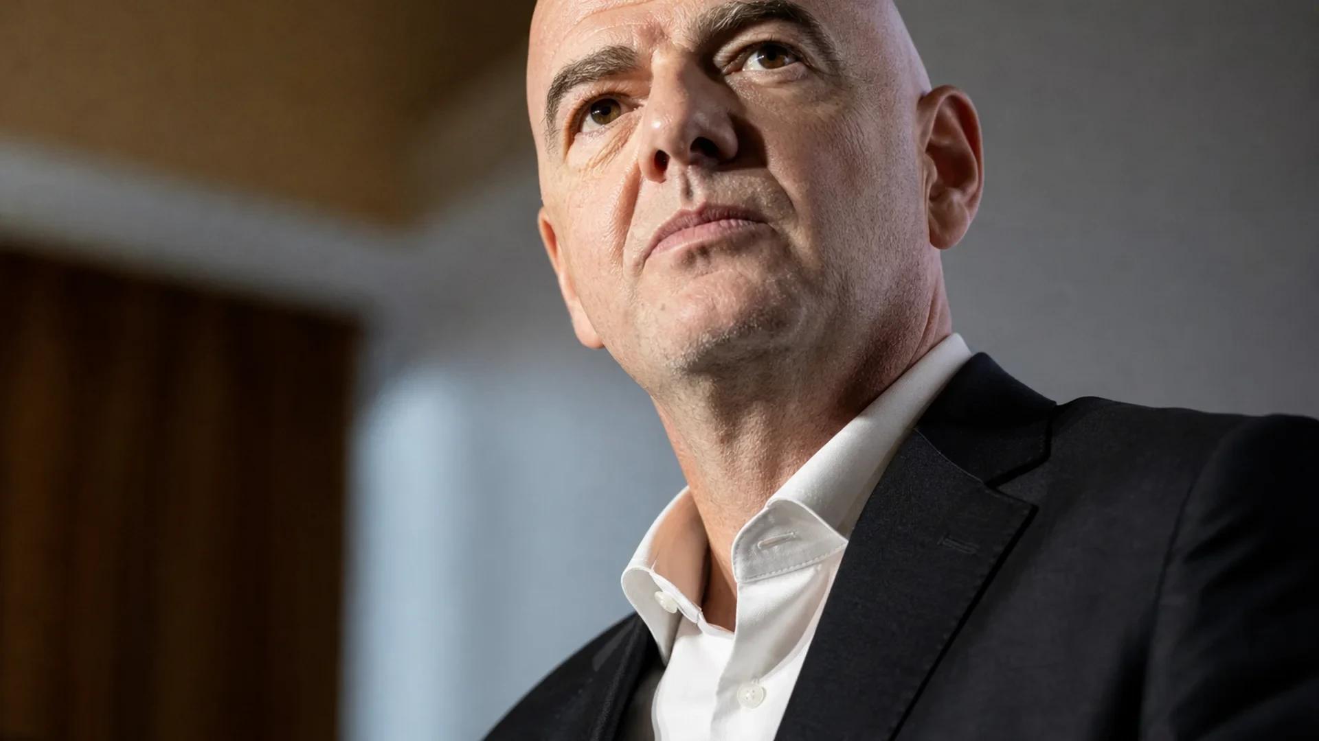 FIFA-president Gianni Infantino i nærbilde med alvorlig og bestemt ansiktsuttrykk, belyst av dramatisk kontrast-lys mot blurred institusjonsbakgrunn.