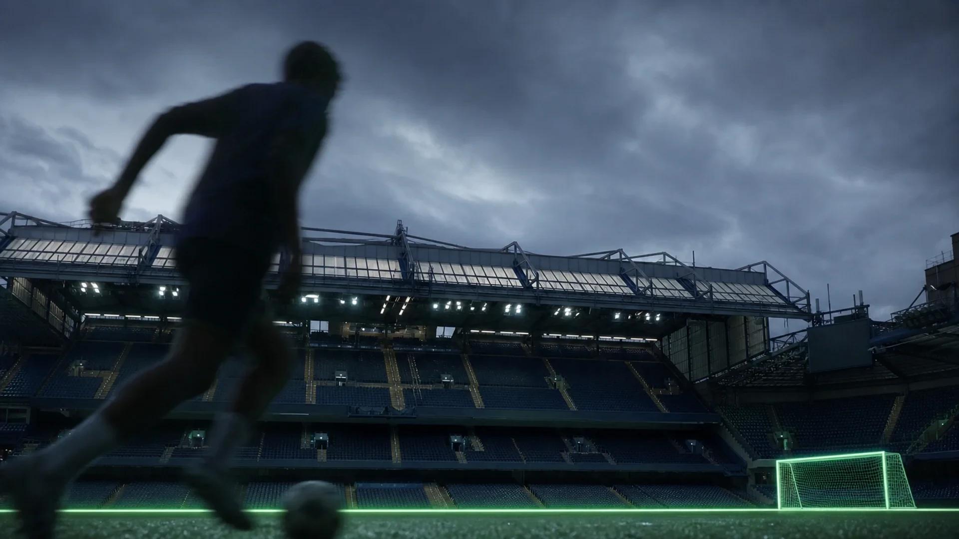 A view of Stamford Bridge stadium with a football pitch and a silhouette dribbling a ball.