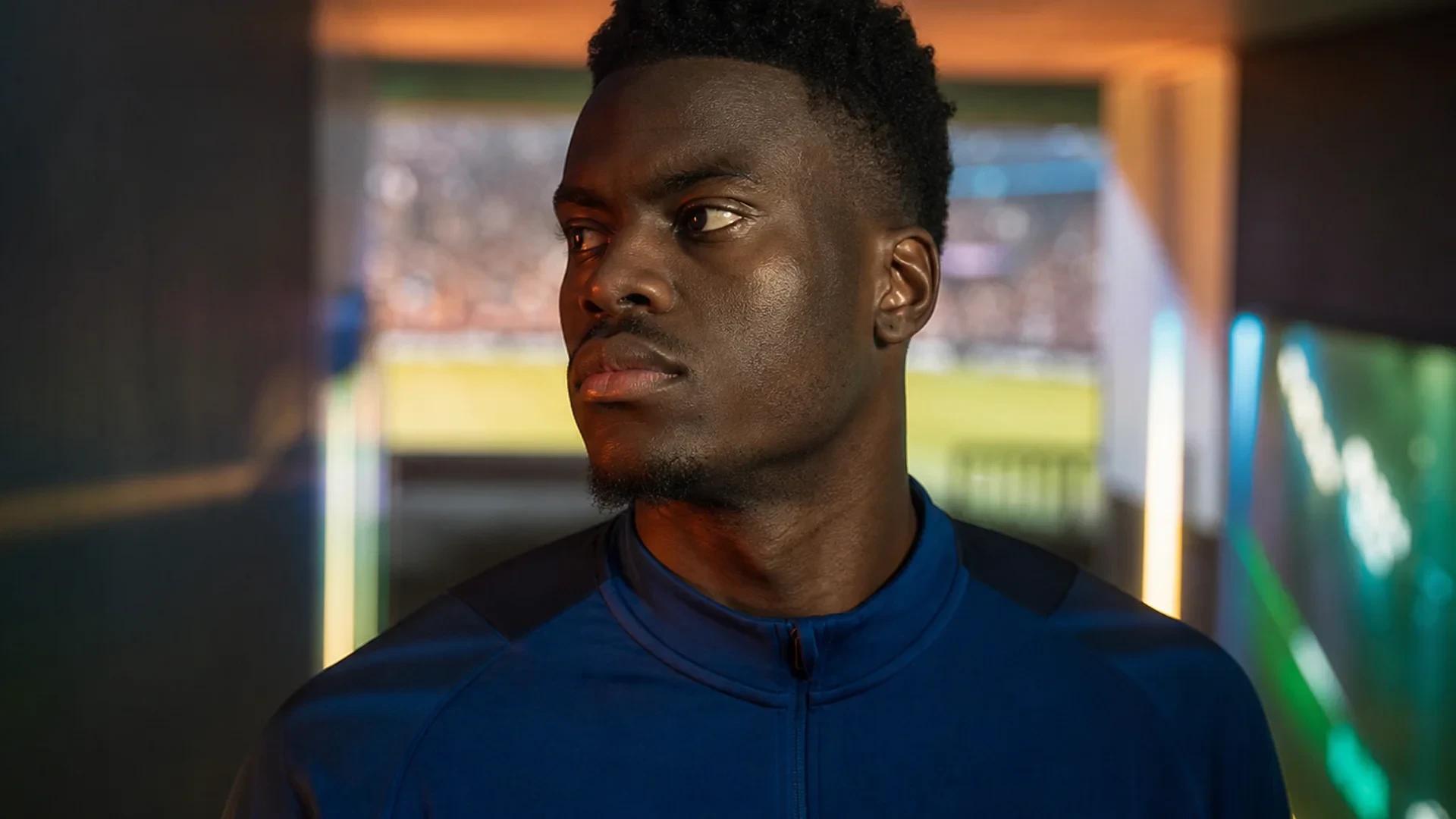 Benoît Badiashile preparing in a stadium tunnel, illuminated by mixed lighting.