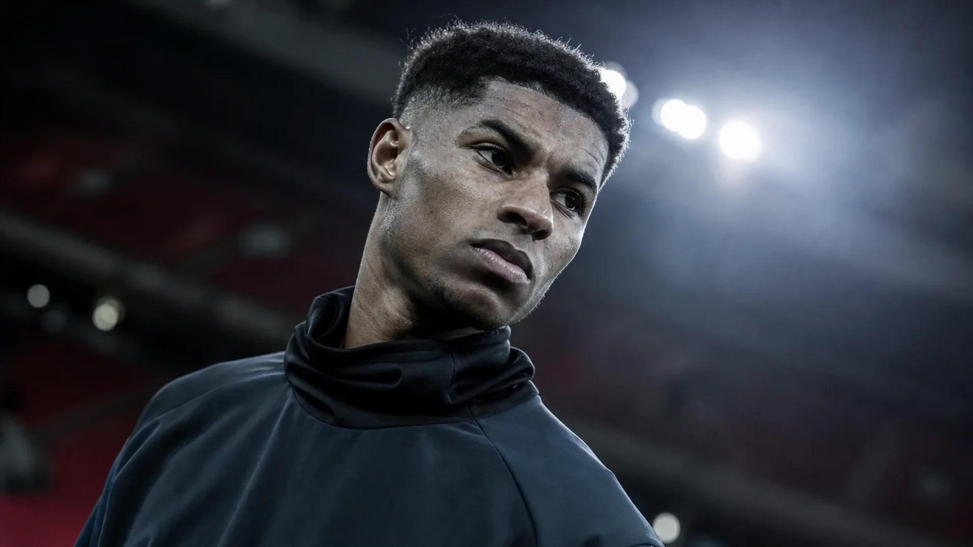 En intens nærbilde av Marcus Rashford i en dramatisk vinkel, med en uskarp bakgrunn av Old Trafford.