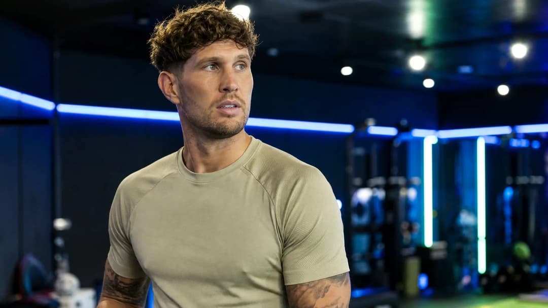 John Stones in a training facility wearing a neutral kit, exuding confidence.