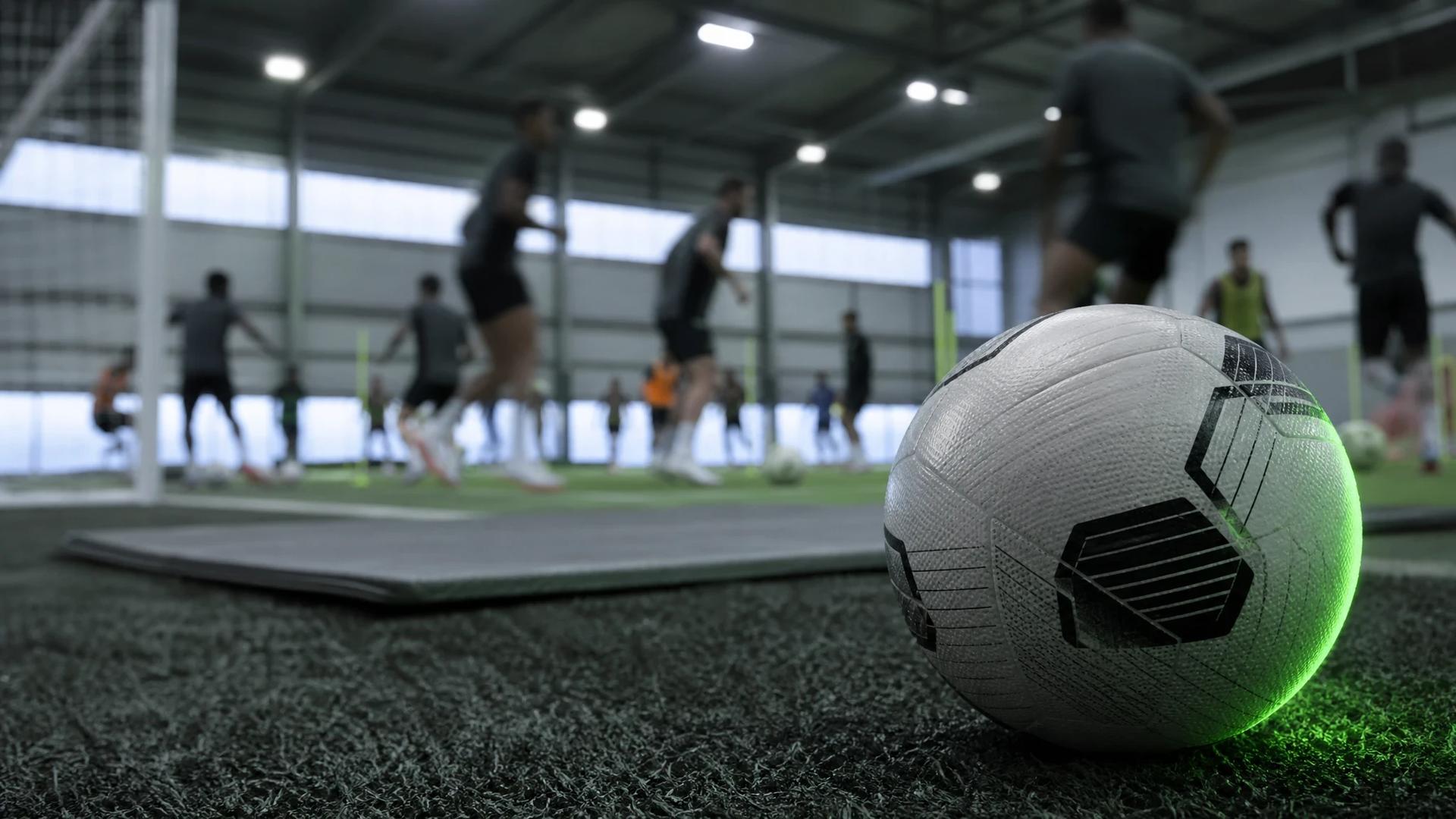 Arsenal players training in a modern indoor facility with a football in focus.