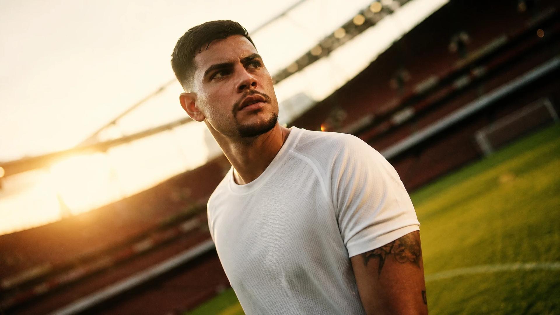 Bruno Guimaraes, a professional footballer, in an anticipatory moment before a match with golden-hour lighting.