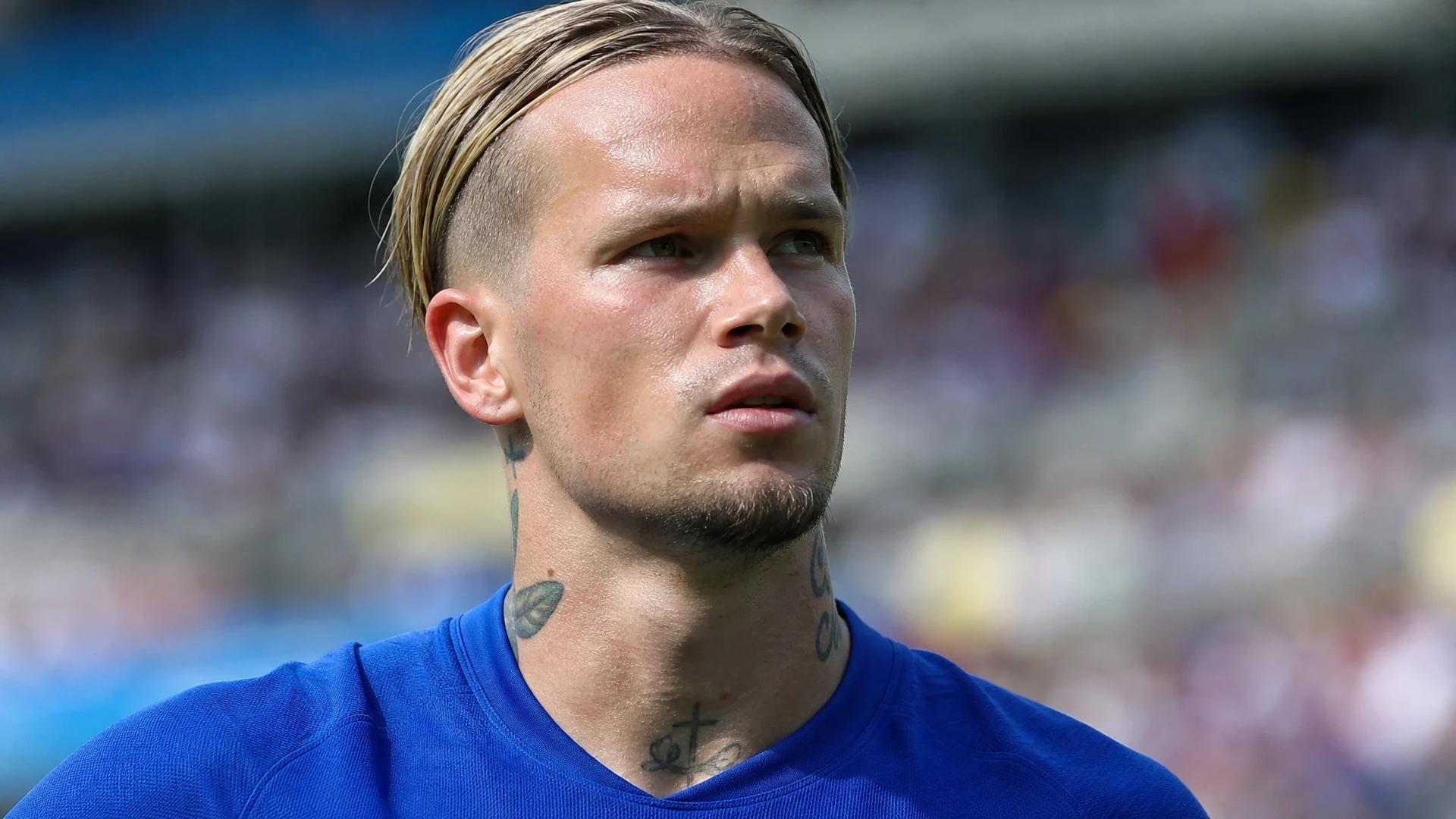 Mykhailo Mudryk stands on the football pitch, looking determined and focused under the midday sun.