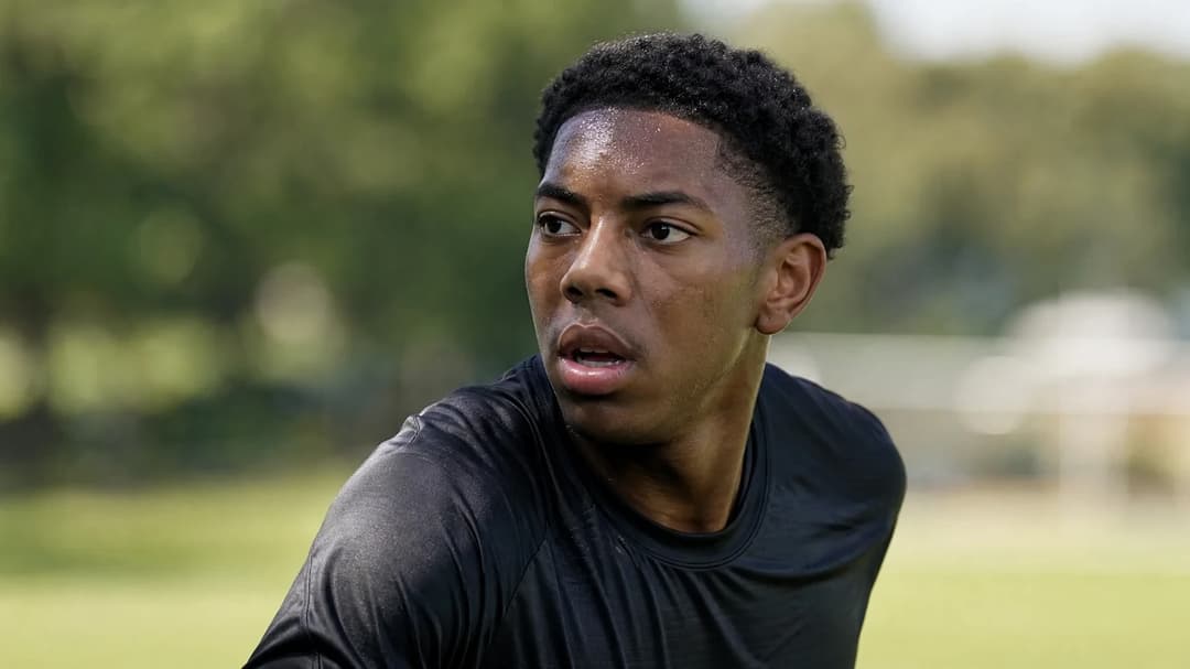 Myles Lewis-Skelly engaged in a training session with dappled light on a football pitch.