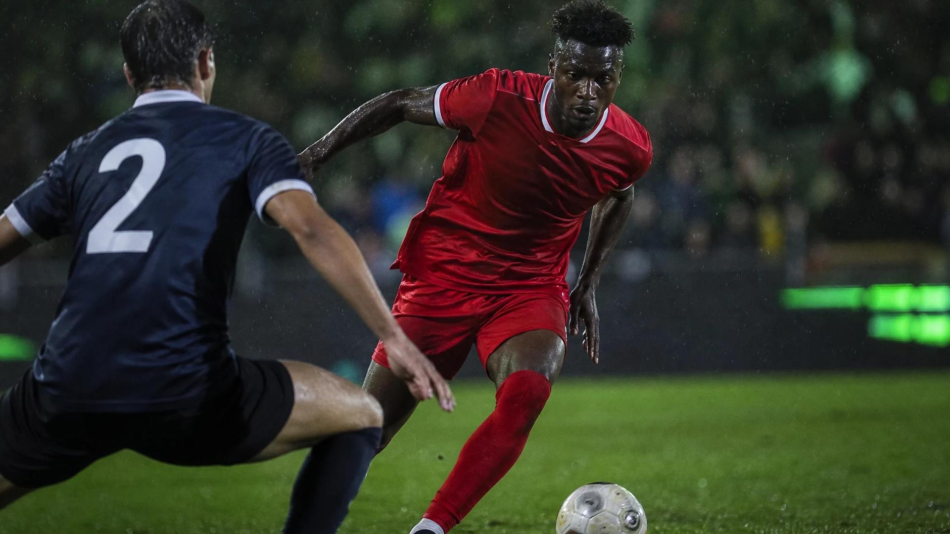 A football player, Emmanuel Latte Lath, dribbles the ball past a defender during a pre-season match.
