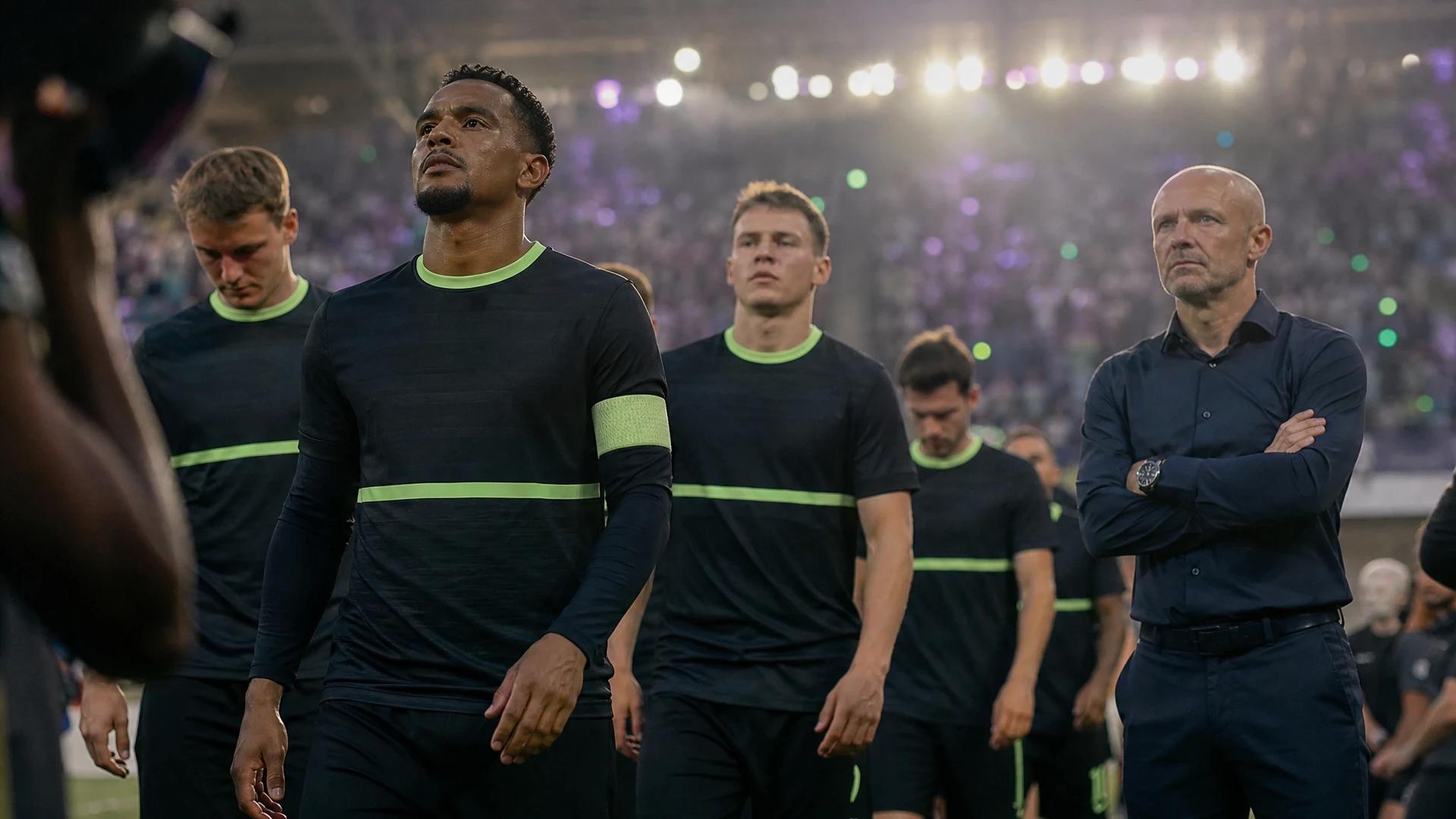 NEC Nijmegen players entering the pitch under spotlight, with blurred enthusiastic crowd in the background.