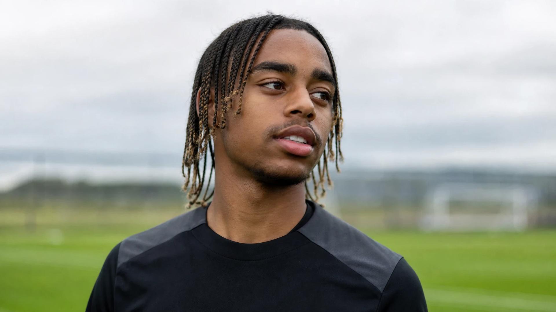 Bradley Barcola training on a football pitch, showcasing a determined expression amidst a blurred background.