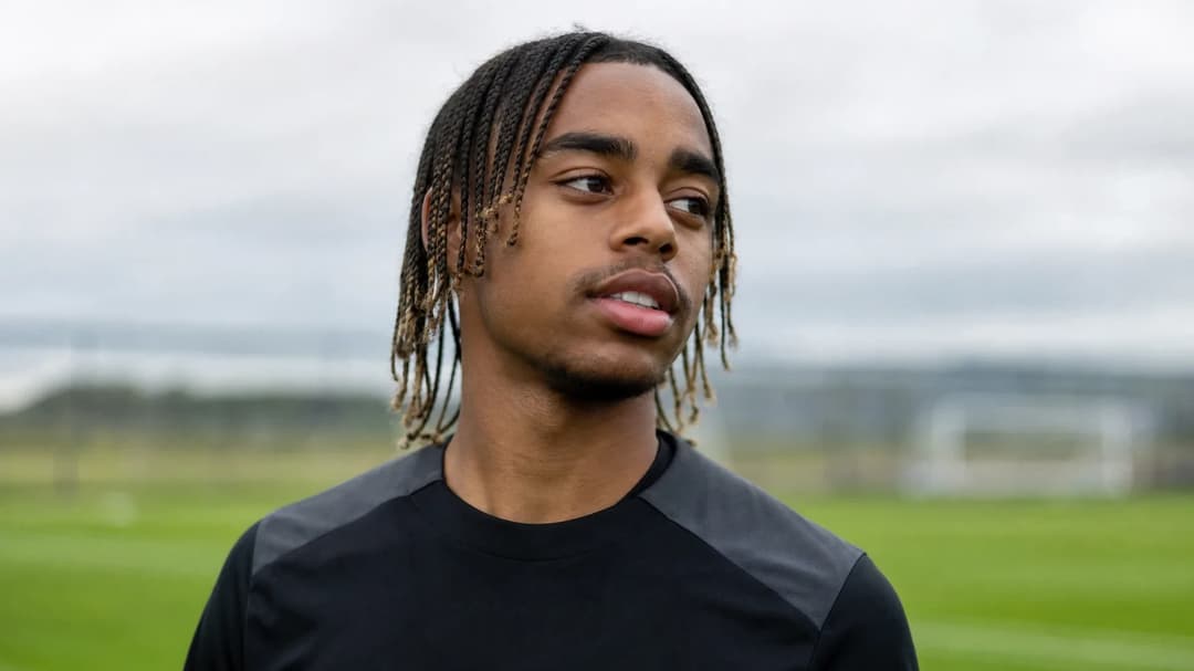 Bradley Barcola training on a football pitch, showcasing a determined expression amidst a blurred background.