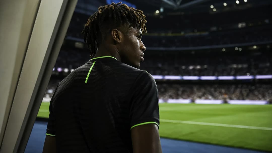 A close-up over-the-shoulder shot of a football player in a stadium preparing for a match.