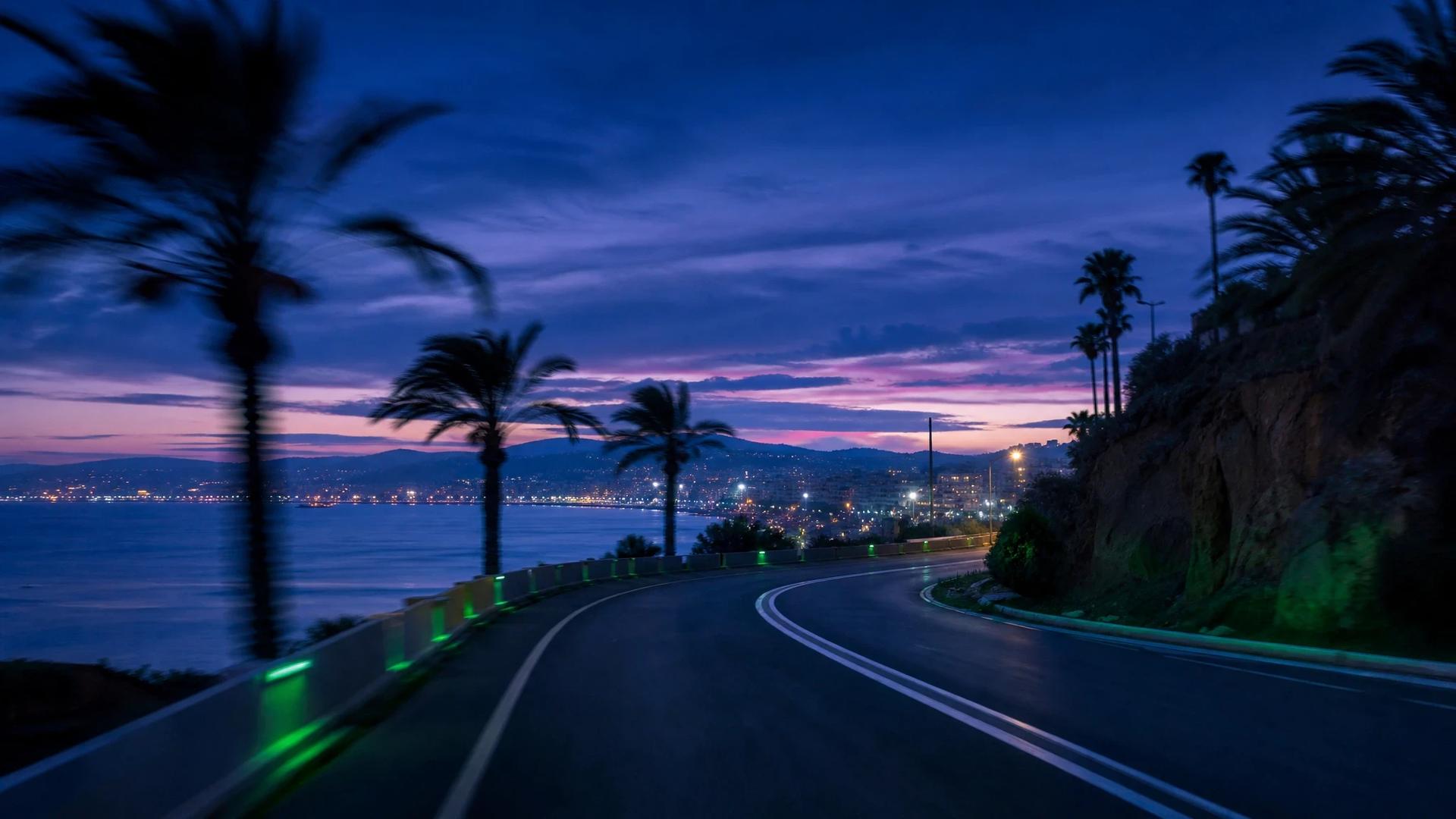 A blurred coastal road at dusk, illuminated by neon green accents.