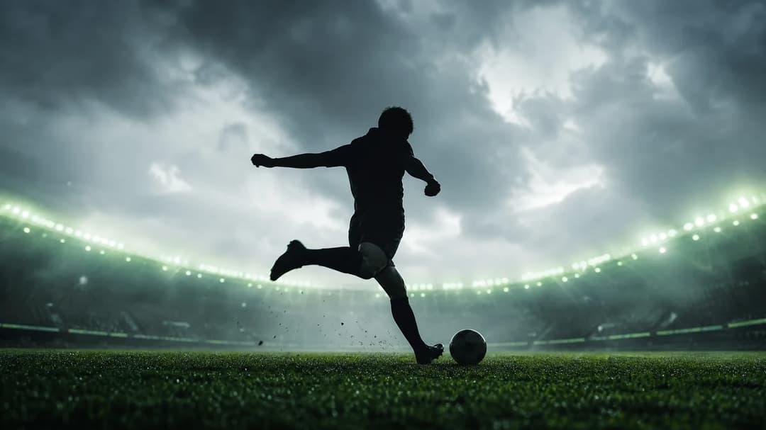 A silhouetted football player in action against a soft, overcast background.
