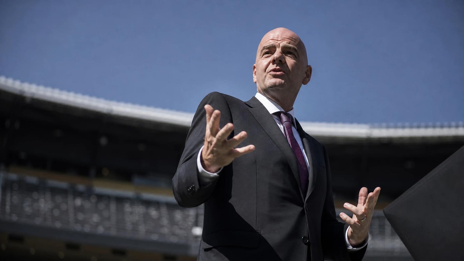 Gianni Infantino stands on a football field, gesturing as he prepares for a significant announcement.