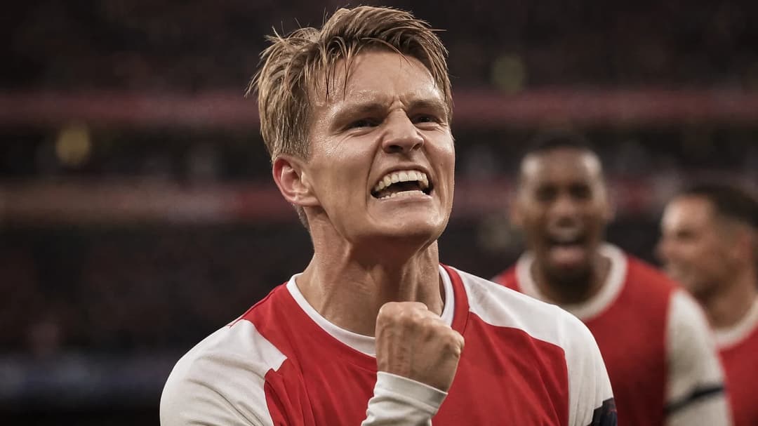 Martin Ødegaard celebrating a goal, showcasing intense emotions in a blurred stadium background.