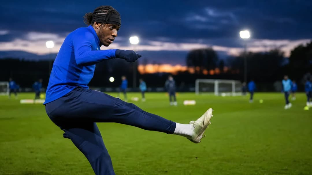 Noni Madueke executing a kick during a training session at dusk.
