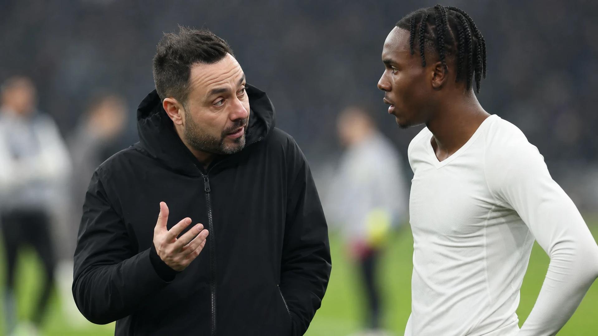 Tottenham manager Roberto De Zerbi speaks with player Mathys Tel during a tactical discussion.