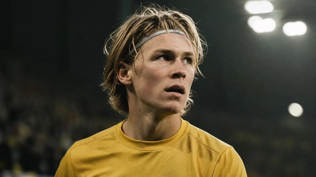 Jens Petter Hauge focused on the game in a vibrant football stadium.