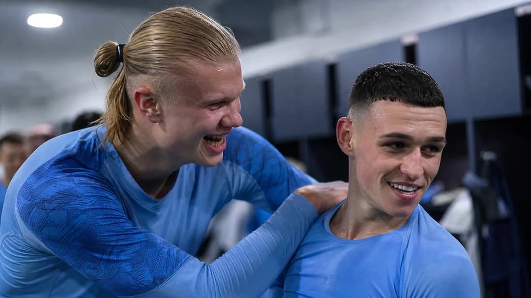 To Manchester City players, Erling Haaland and Phil Foden, interacting in a celebratory locker room.
