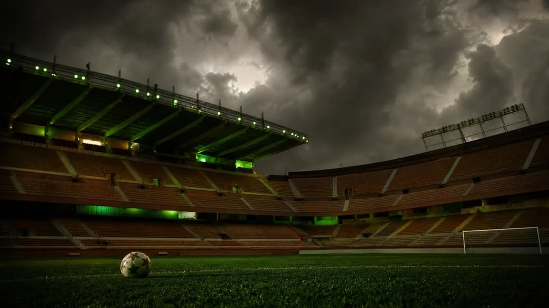 An empty Ramón Sánchez Pizjuán stadium under dark storm clouds.