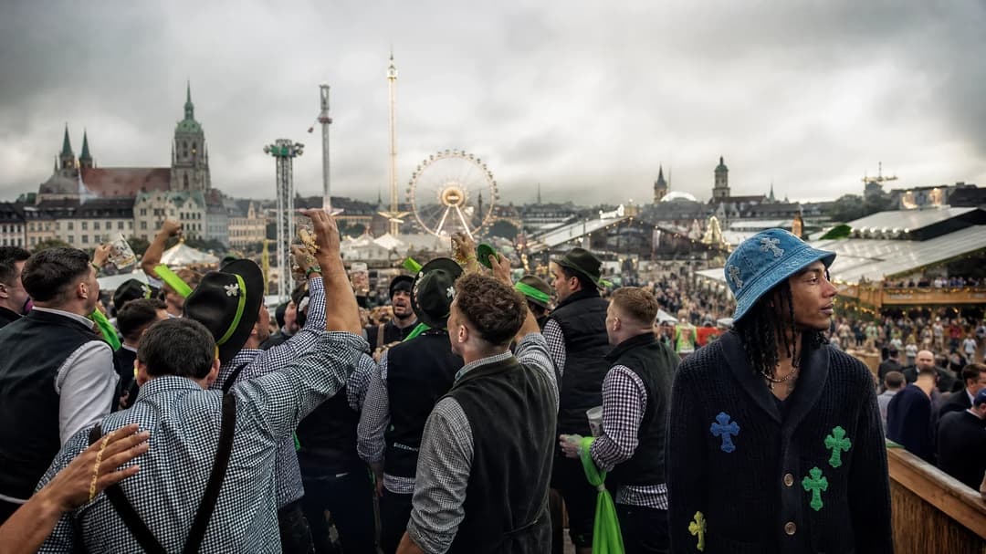 A panoramic view of Oktoberfest in Munich, with a crowd in traditional Bavarian attire and a distinct figure wearing a blue hat.