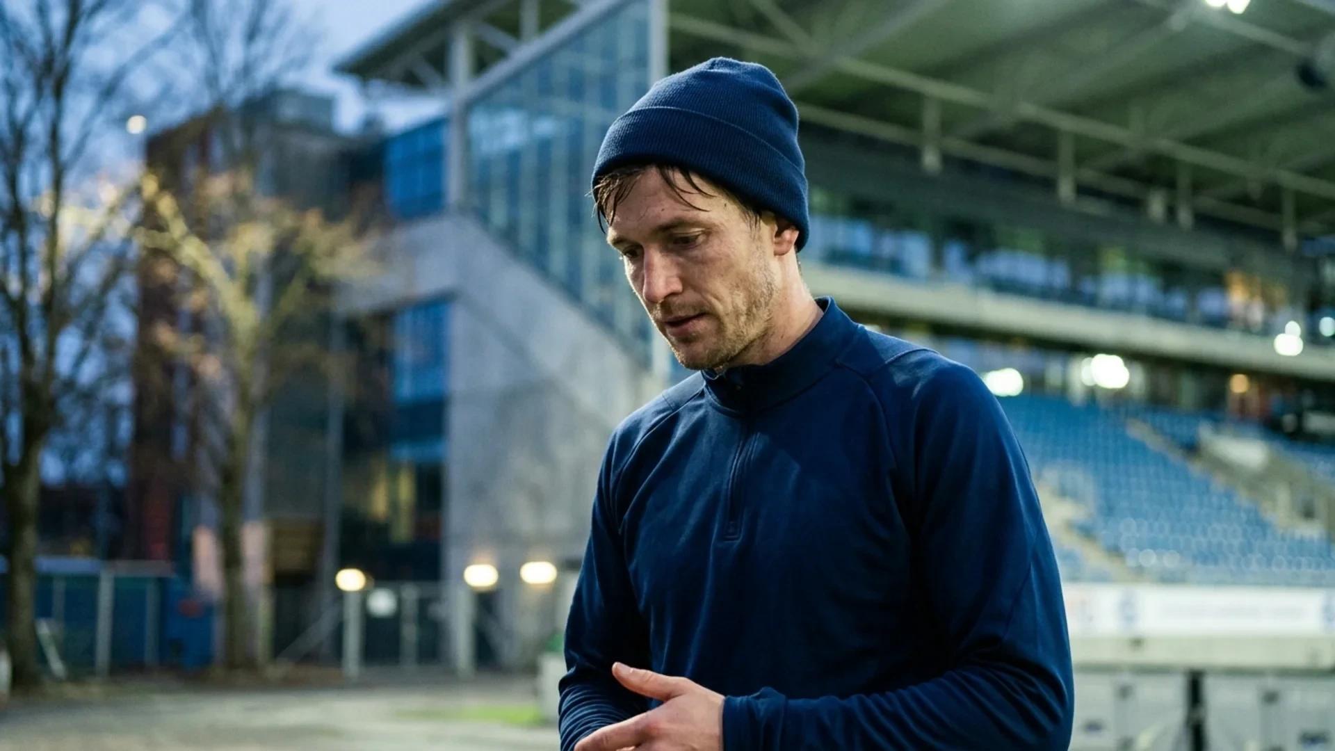 A football player from Vålerenga reflecting after a match, illuminated by dappled light in the background.