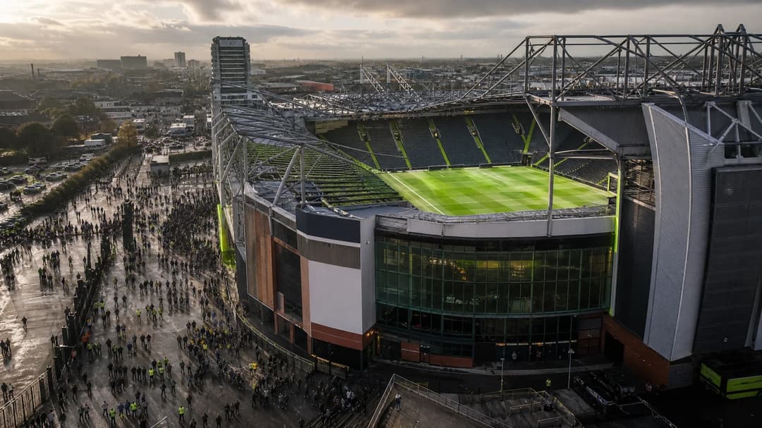 A view of Old Trafford stadium, showing the exterior under natural lighting with hints of neon green accents.