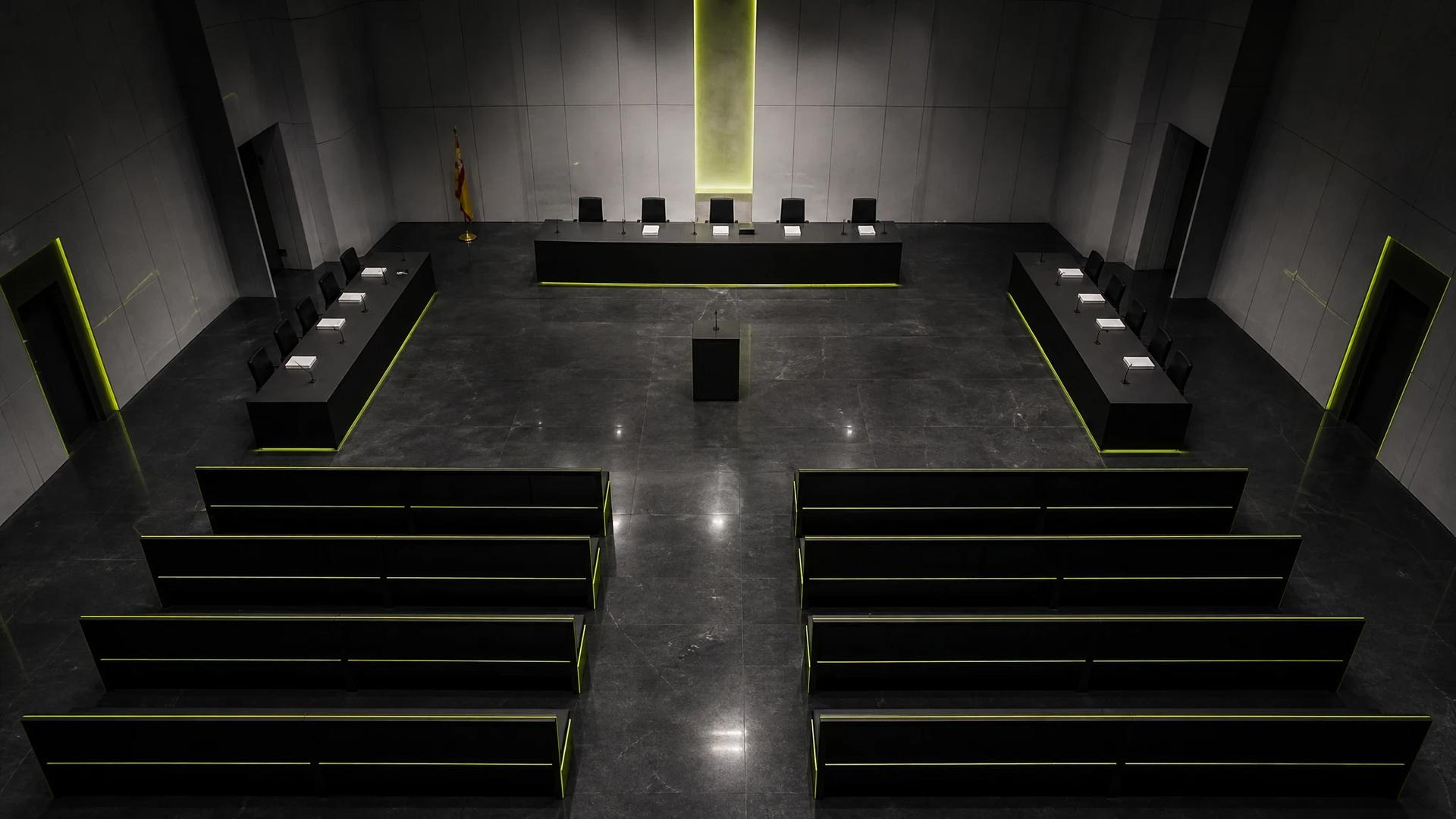 An empty Madrid courtroom with cold lighting, suggesting the tension of an upcoming legal battle.