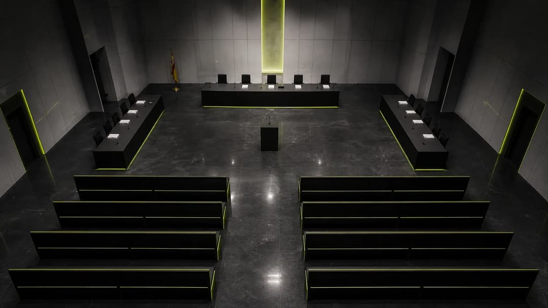 An empty Madrid courtroom with cold lighting, suggesting the tension of an upcoming legal battle.