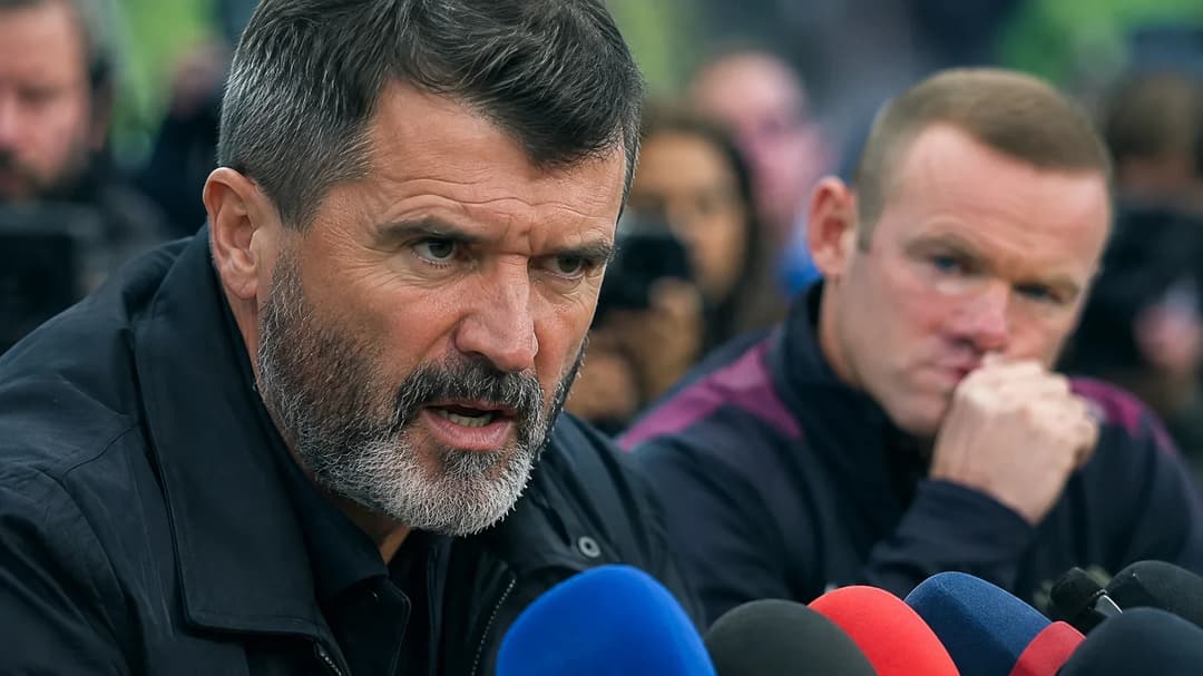 Roy Keane speaks passionately at a press conference with Wayne Rooney visible in the background.