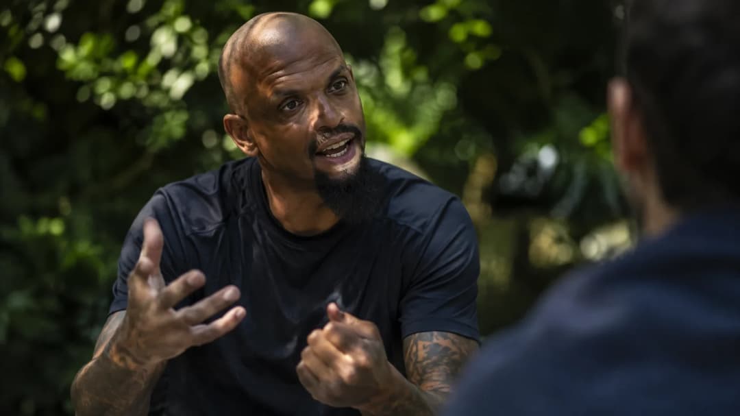 Felipe Melo animatedly gestures while speaking, framed in dappled sunlight.