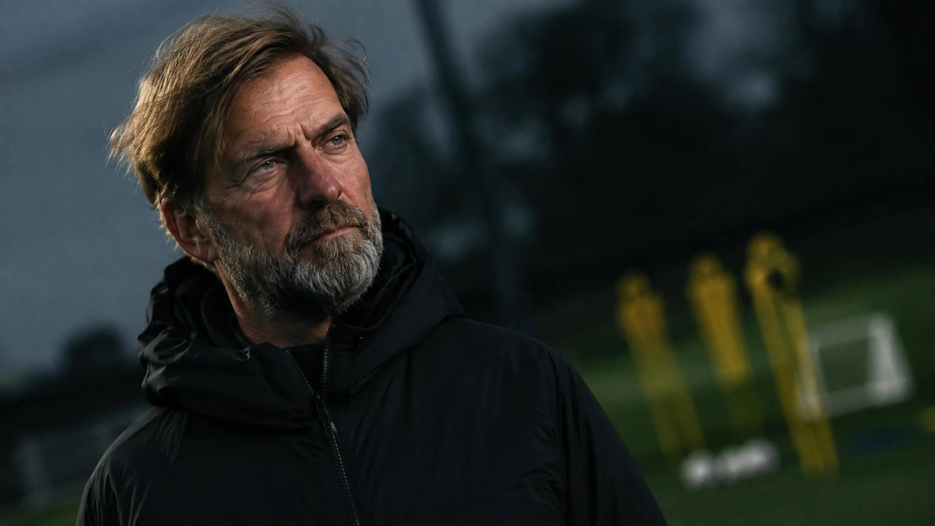 Jurgen Klopp in a contemplative pose on a football training ground.