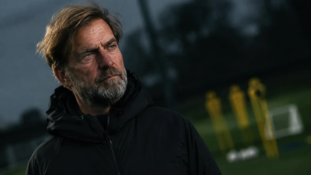 Jurgen Klopp in a contemplative pose on a football training ground.