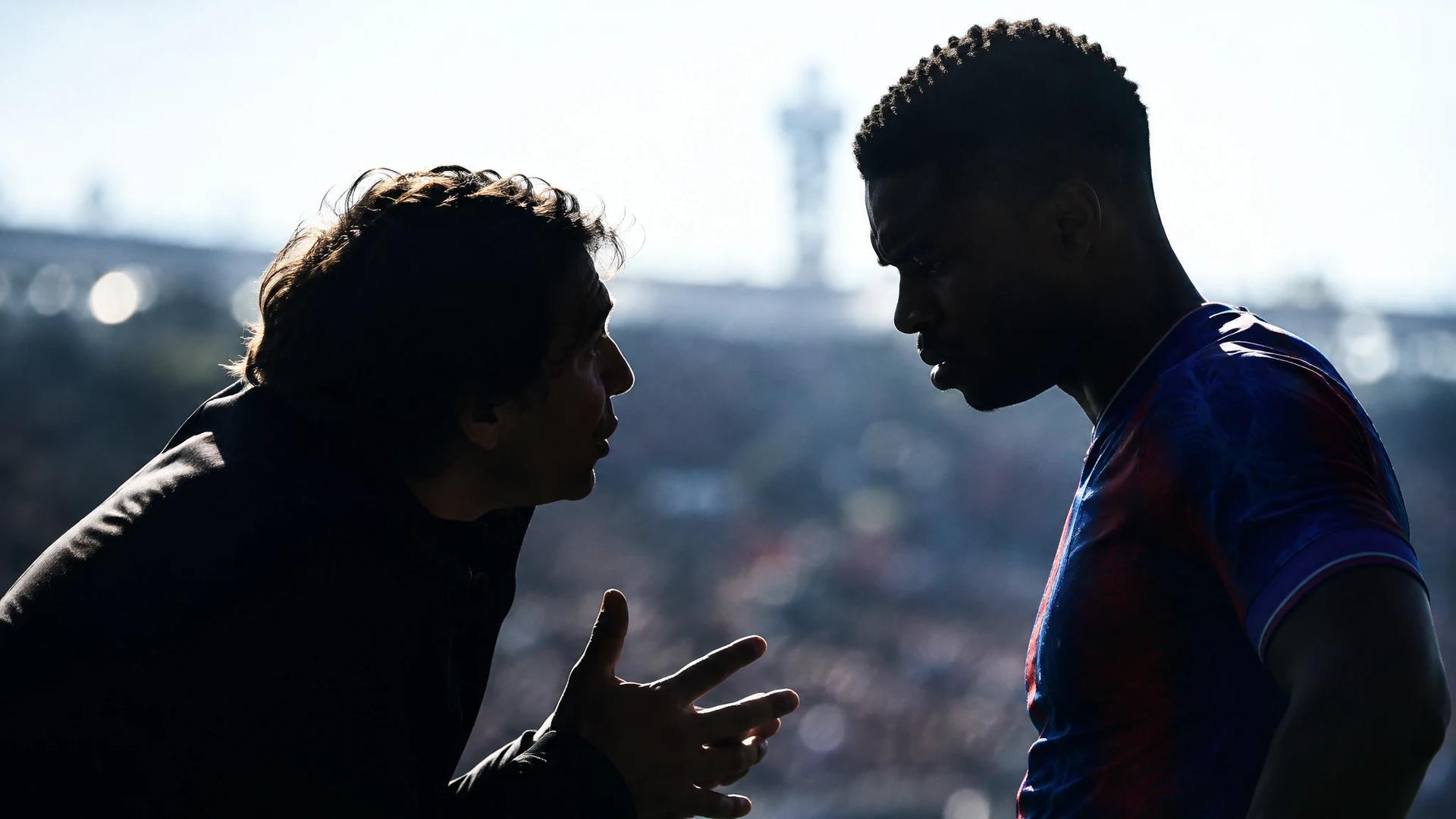 Rui Pinto and Marc Guéhi silhouetted against a bright football pitch.