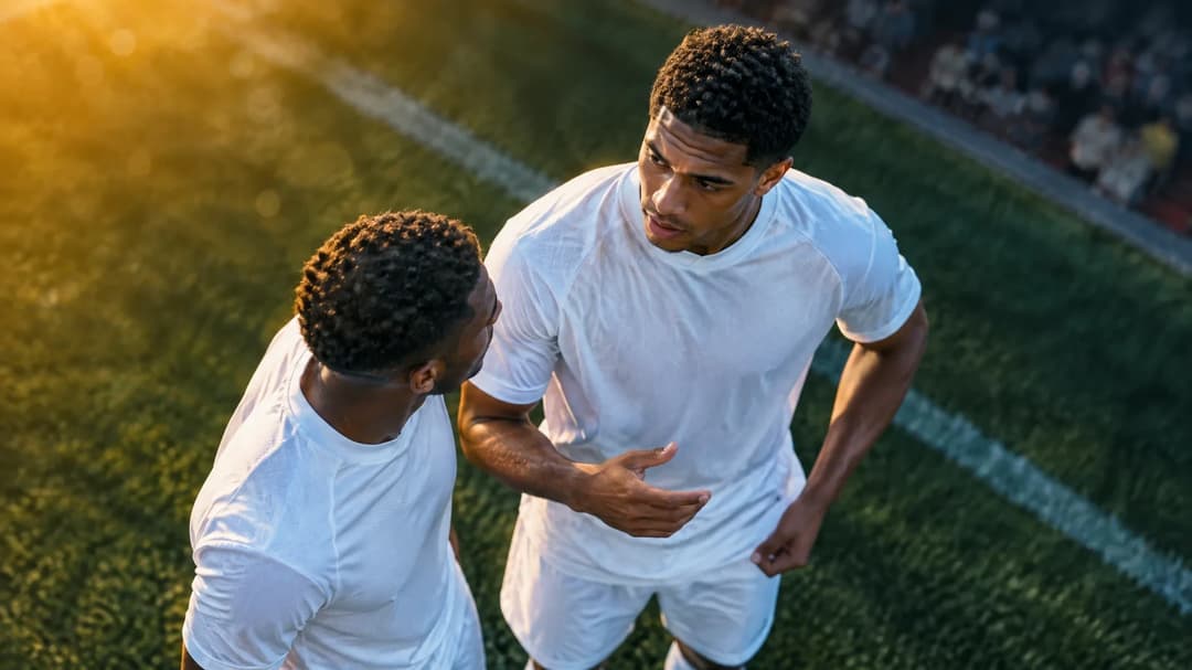 Jarell Quansah and a teammate engaged in conversation on the football pitch.