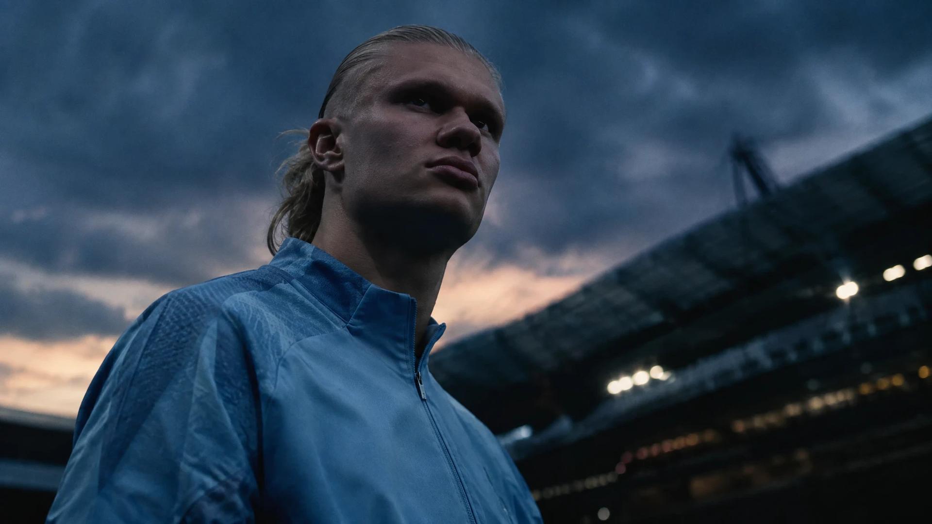 Erling Haaland in a tense moment with a blurred stadium background.
