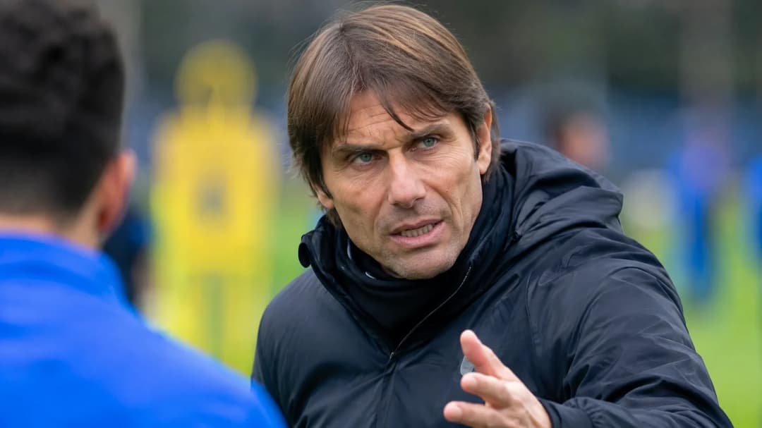Antonio Conte intensely engaged in a football training session, with blurred players in the background.
