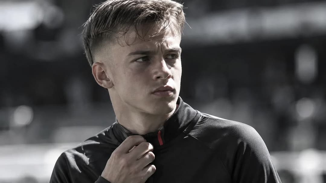 Lennart Karl står konsentrert ved en fotballsidelinje i hardt sollys.