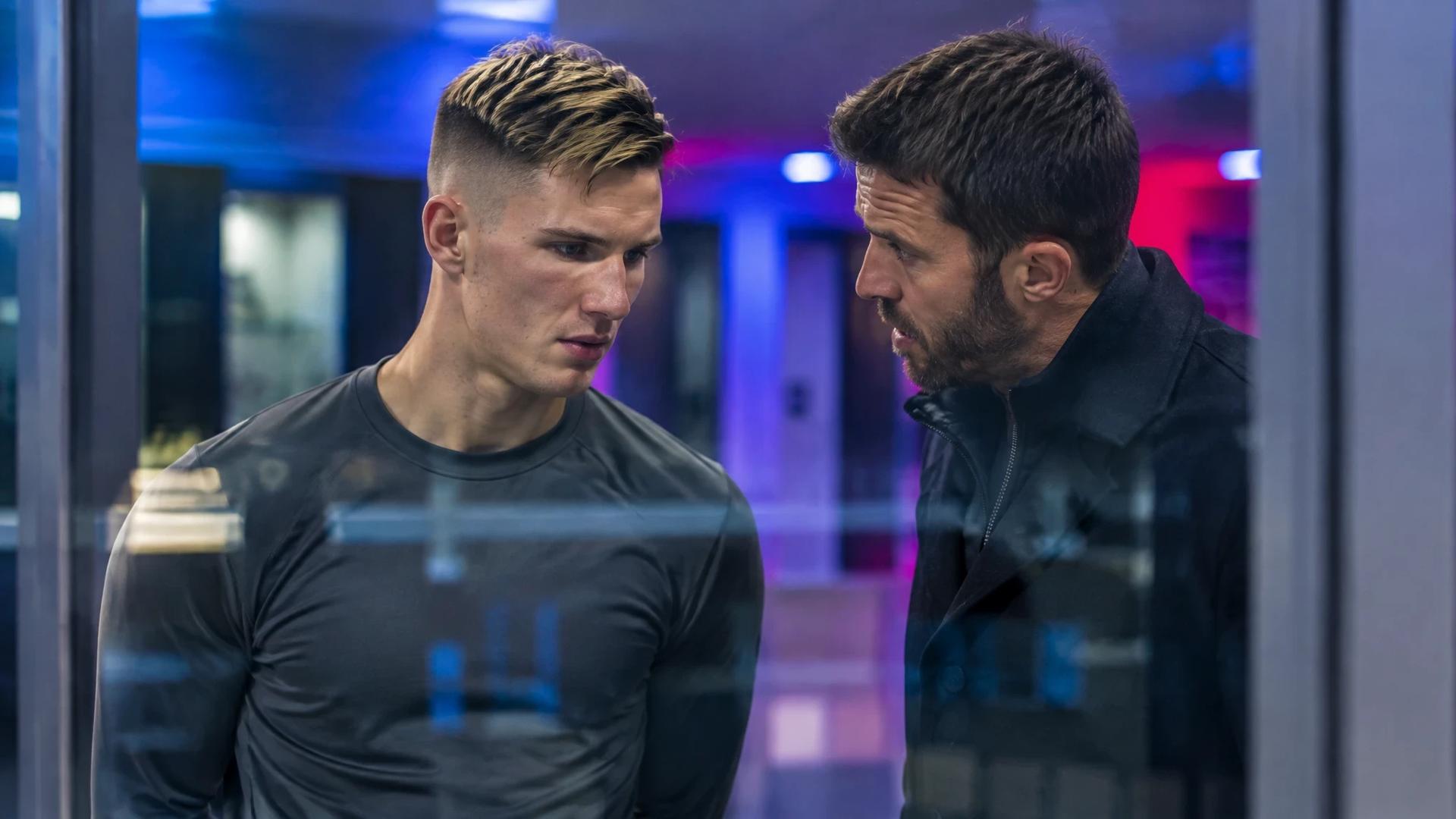 Benjamin Šeško og Michael Carrick står i en rolig samtale i en stadionkorridor, sett gjennom glass.