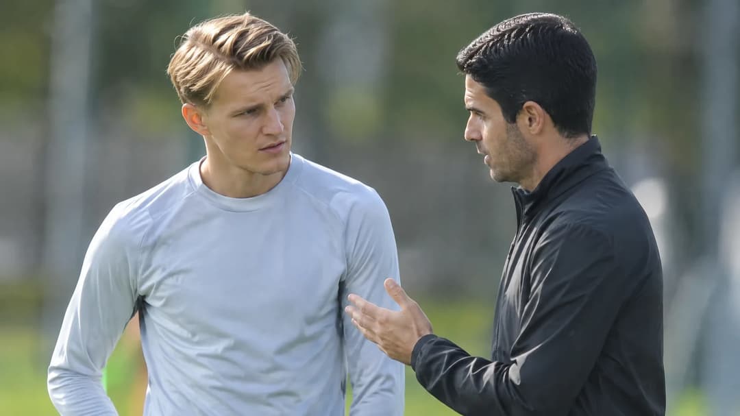 Martin Ødegaard og Mikel Arteta snakker sammen på en fotballtreningsbane.