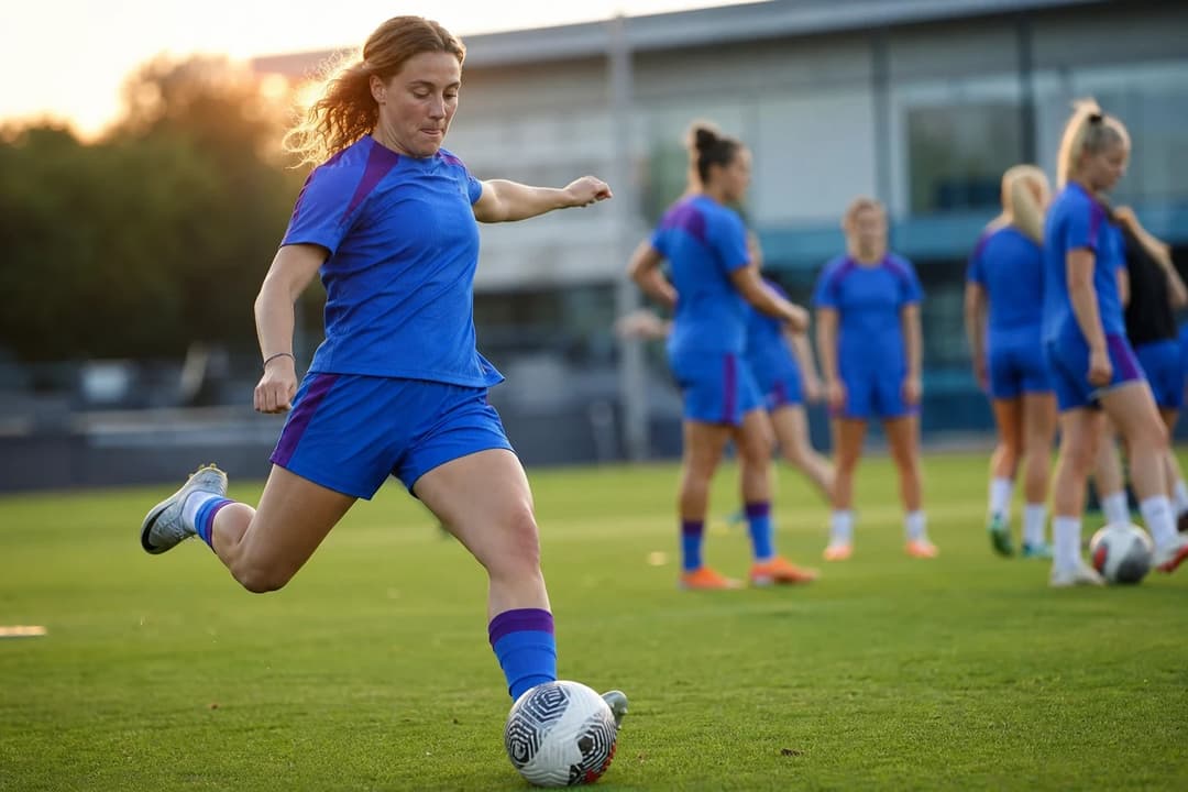 Brighton & Hove Albion captain Maisie Symonds kicking a soccer ball on the training ground surrounded by teammates.