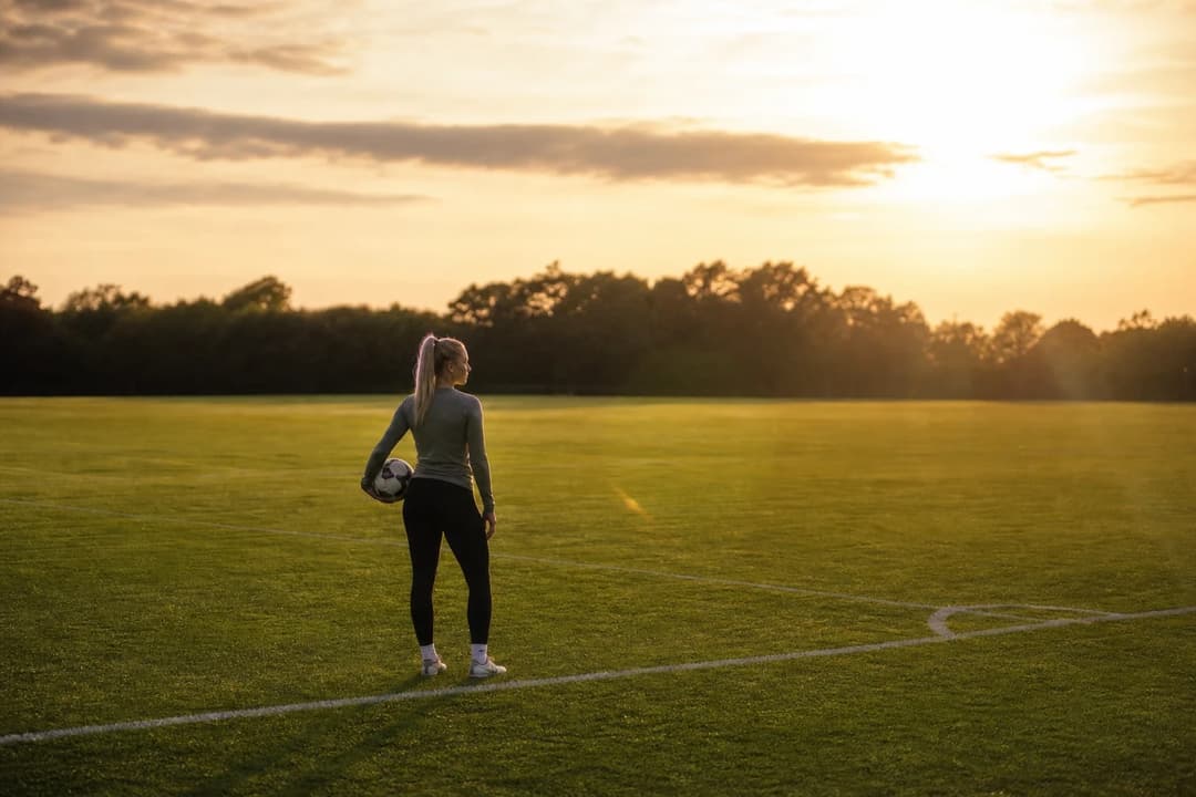 Katie Bradley stands alone on a sunlit training pitch in golden-hour light, holding a football, facing a new chapter with Newcastle United.