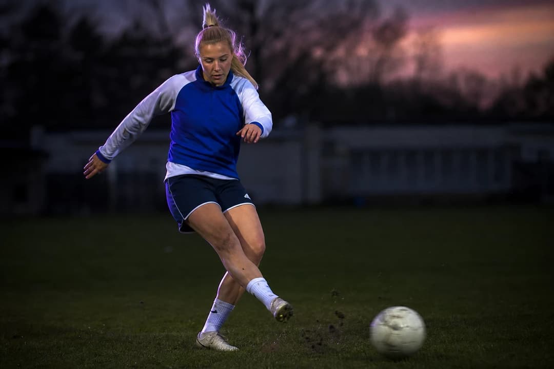 A young female footballer, Signe Søndergård, practices her footwork on a training pitch.