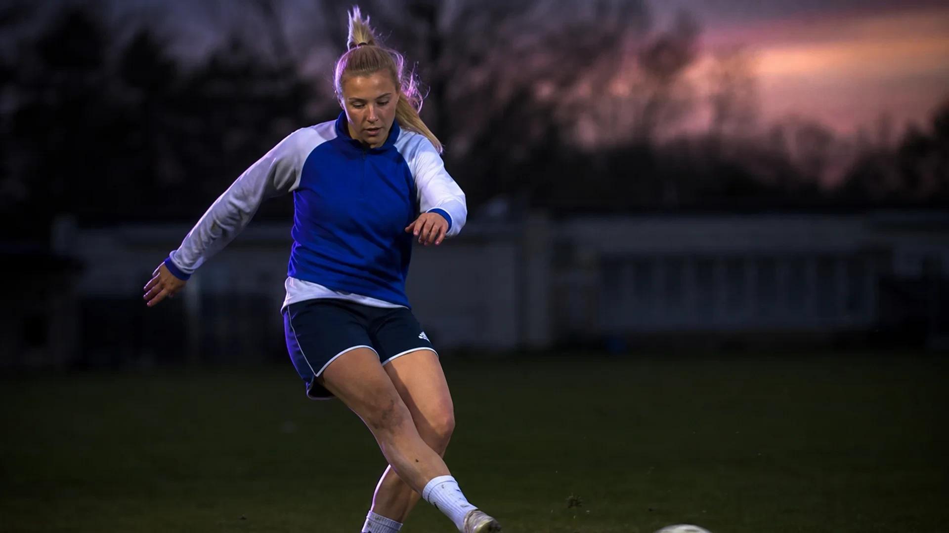 A young female footballer, Signe Søndergård, practices her footwork on a training pitch.